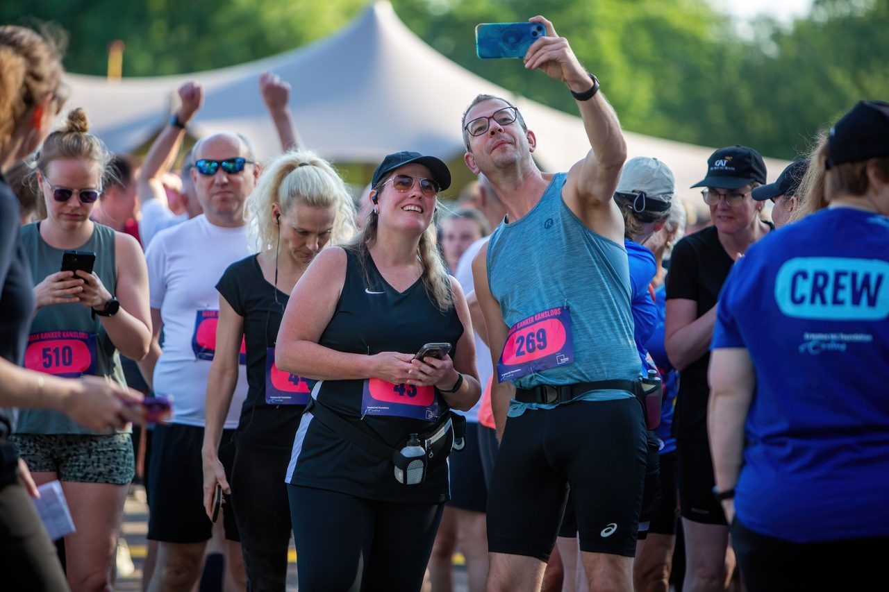 Hardlopers met startnummers maken een selfie voor de start van een benefietloop