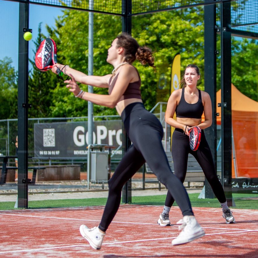 Padelspeelster slaat een volley terwijl haar partner toekijkt