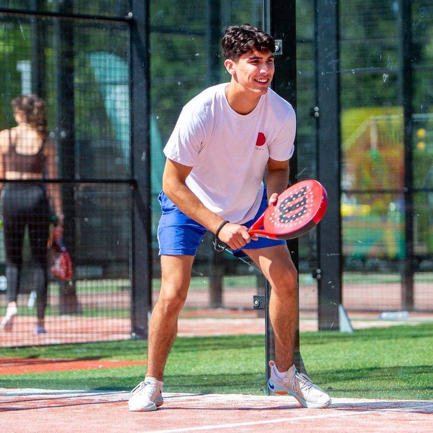 Lachende padelspeler wacht in de baan op de bal