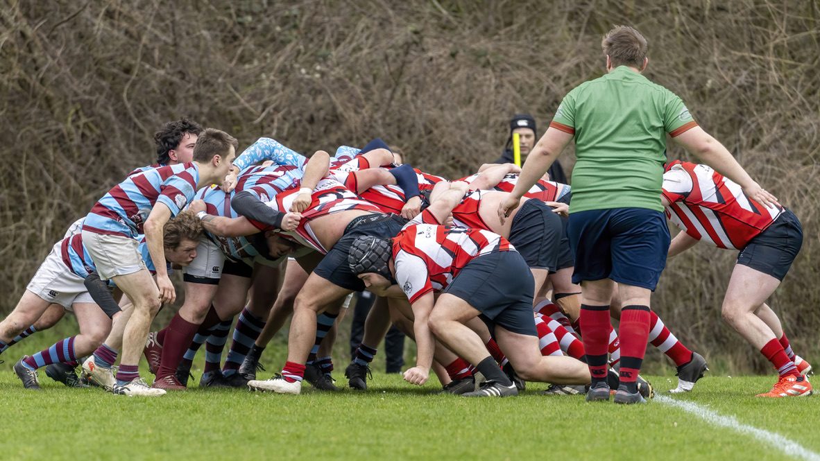 Twee rugbyteams zetten de scrum, de scheidsrechter staat ernaast