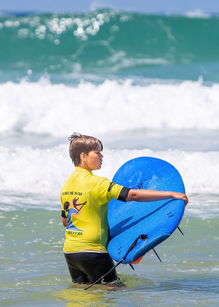 Jonge surfer loopt met zijn board de zee in