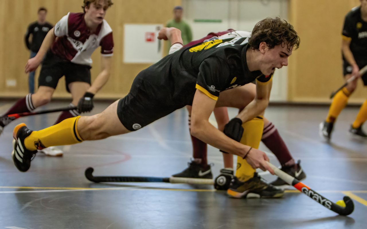 Zaalhockeyer duikt horizontaal naar de bal
