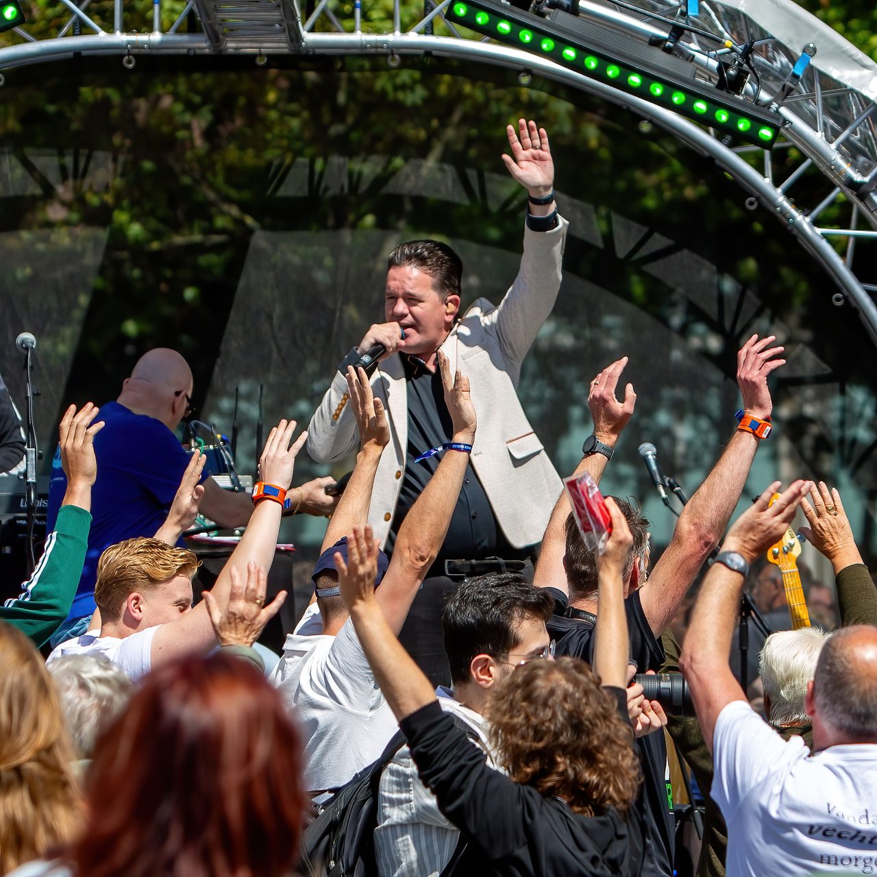 Zanger op een podium met het publiek dat de handen in de lucht steekt
